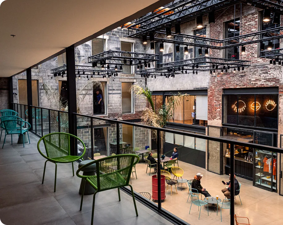 The atrium of Billy Penn Studios in Philadelphia: a glass-railed balcony above a courtyard café in a brick and stone industrial building.