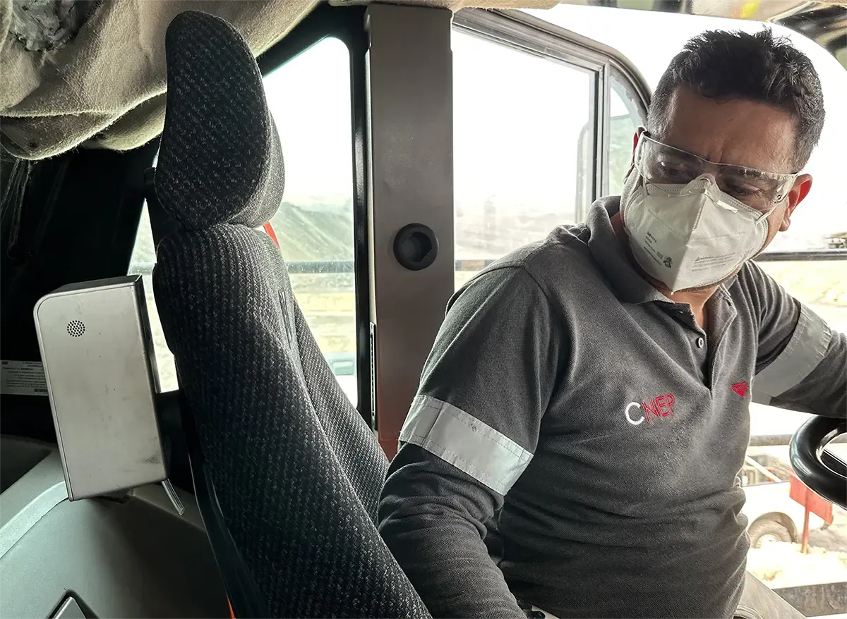 A mining equipment operator seated in heavy equipment, looking at an Aethair PRO mounted beside the seat.