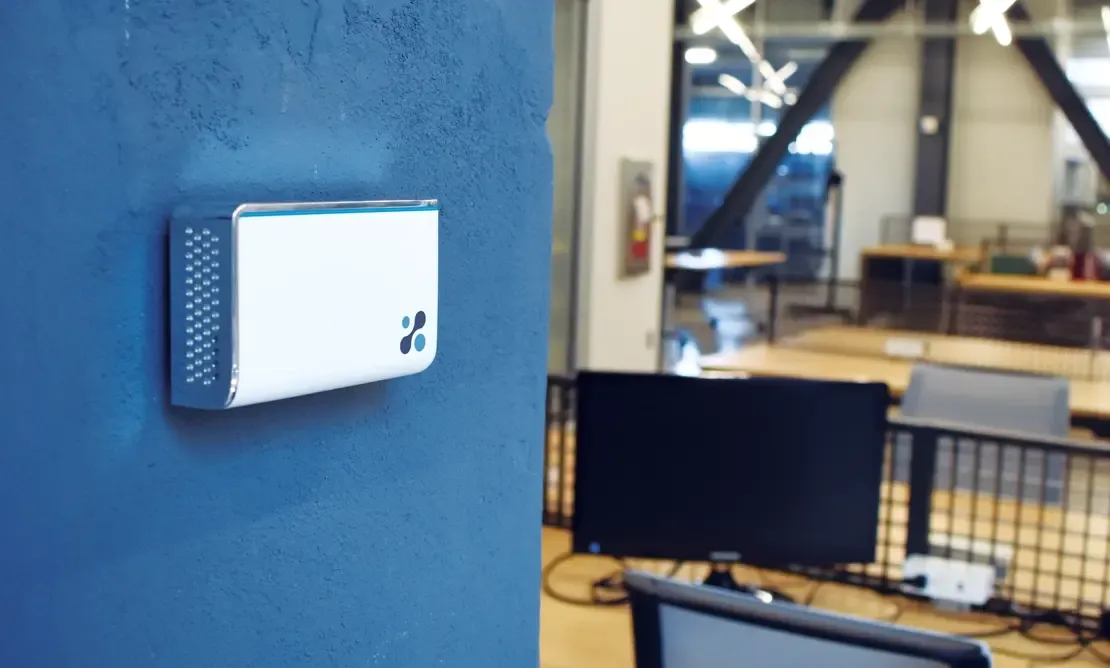 Aethair IAQ mounted on a concrete wall inside a modern workspace.